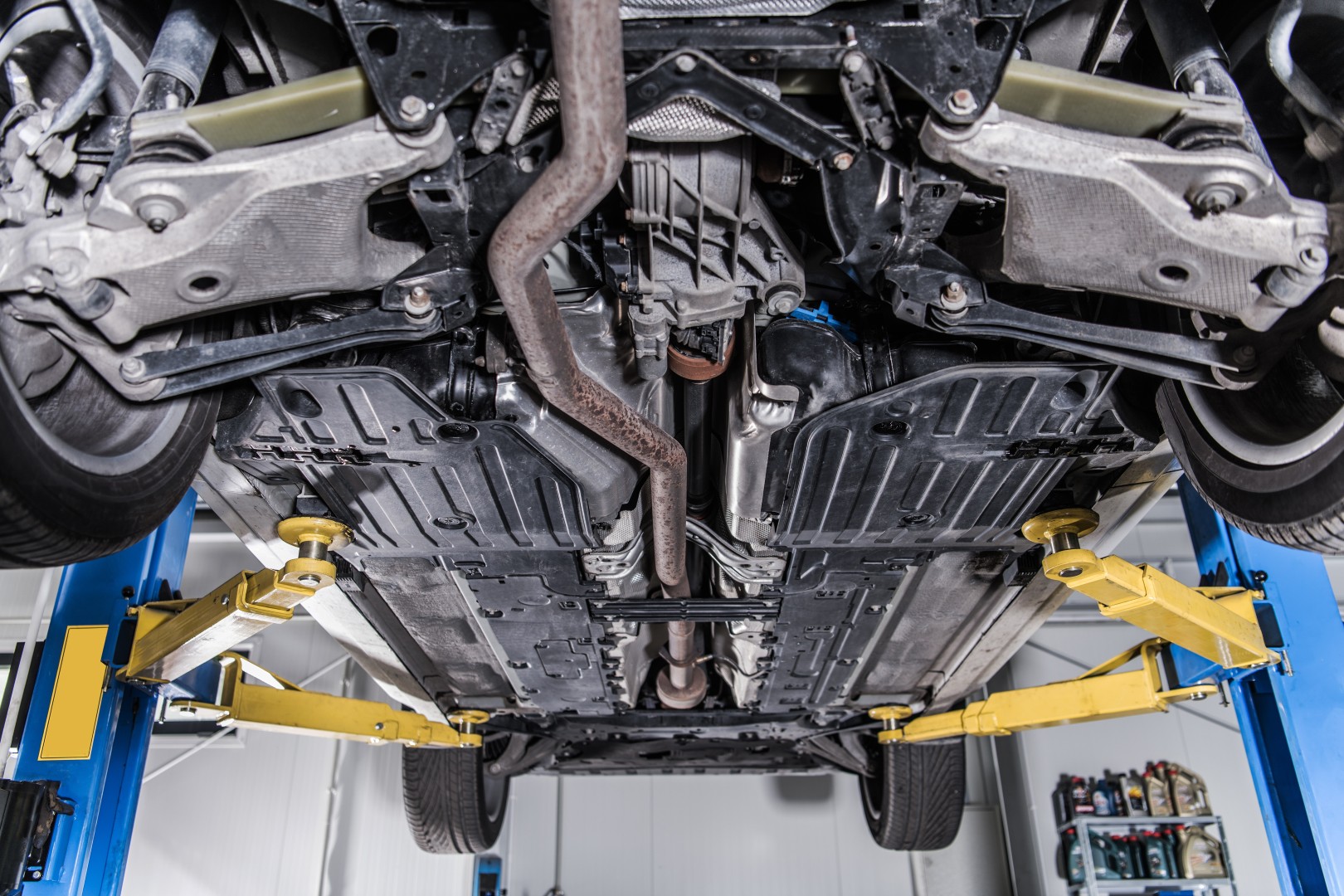 Car on a Heavy Duty Industrial Lift. Repairing Broken Vehicle. Auto Service Theme. Looking Undercarriage.
