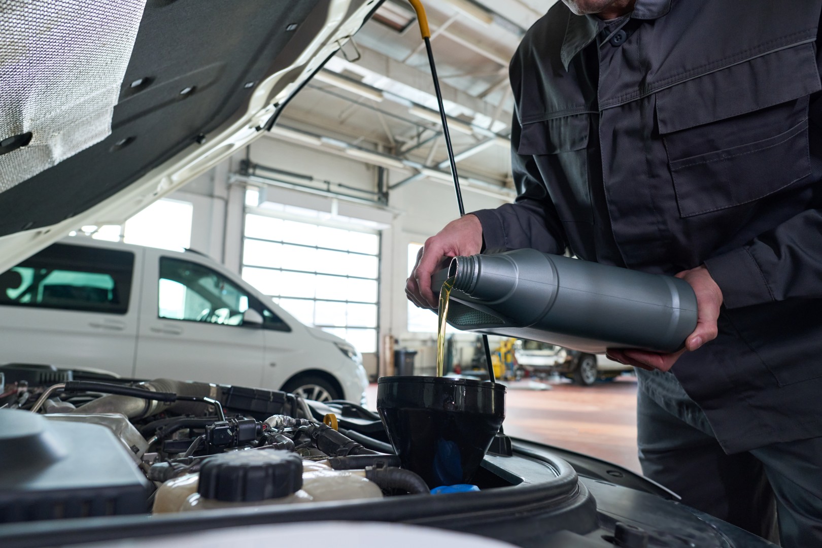 Man Adding Fresh Oil to Engine during Vehicle Servicing